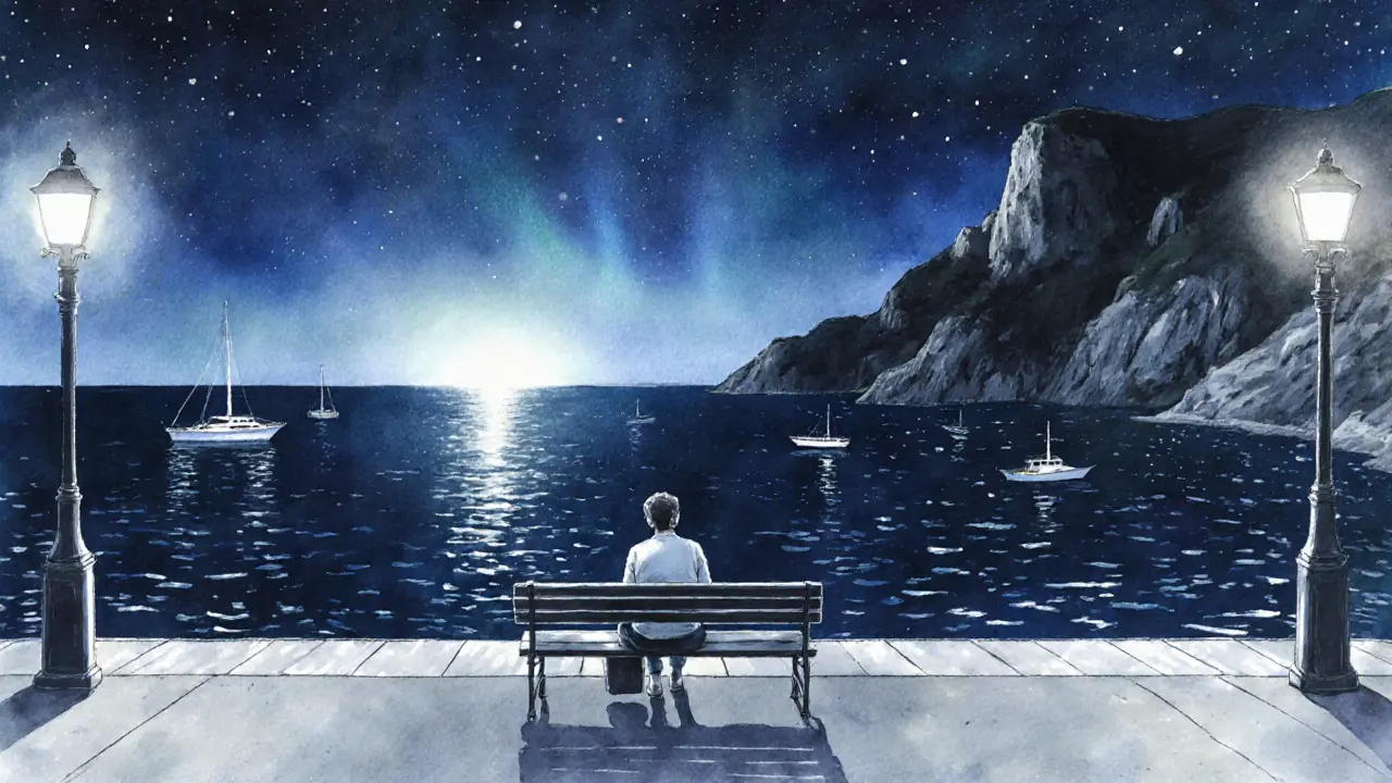 Solo traveler sitting on a bench overlooking the Mediterranean at night.